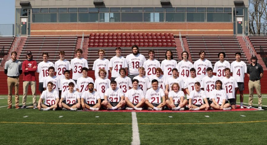 Men’s lacrosse 2021–22 team and coaching staff stand on Bailey Field.